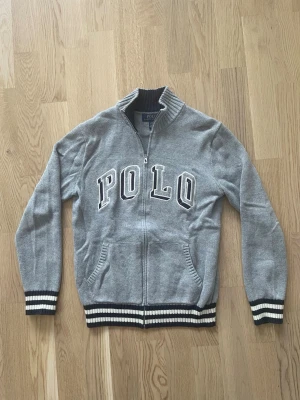 Grå stickad kofta från Polo Ralph Lauren - (14-16) - Jag säljer den här gråa stickade koftan från Polo Ralph Lauren i storlek 14-16. Jag skulle säga att det motsvarar XS. Den är i fint skick utan skador och defekter. Tveka inte att höra av er!