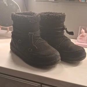 Svarta boots från Everest  - Svarta boots från Everest med mysig päls runt skaftet och snörning som går runt skon. Ovandel i mocka och syntet, grov sula och rund tå. Perfekta för kalla dagar när du vill hålla stilen och värmen. Inukki liknande.