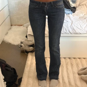 Wrangler bootcut jeans mörkblå W26 L32 - Mörkblå jeans från Wrangler med klassisk bootcut-passform och snygga kontrastsömmar. Jeansen har fem fickor, bälteshällor och den ikoniska W-detaljen på bakfickan. Tillverkade i slitstarkt denim med en skön känsla.