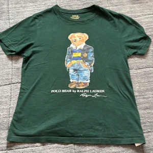 Grön Polo Bear t-shirt från Ralph Lauren - Mörkgrön t-shirt från Polo Ralph Lauren med tryck på bröstet.  Skick 9/10 syns inte att den är använd💫 Nypris 799kr mitt pris 249✅ Vid minsta intresse hör av dig! Passar mellan 150-165