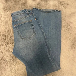 Blå jeansbyxor från H&M , strl 38 - Snygga blå jeansbyxor från H&M i storlek 38. Klassisk femficksmodell med bälteshällor och knappstängning. Jeansen är i bootcut/flare. Endast använda runt tre gånger. Lite slitna längst ner då de har varit för långa.