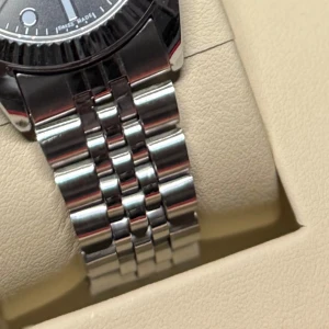 Silver swiss klocka - SKRIV FÖR FLER BILDER! Säljer en stilren återställd vintage klocka med klassisk jubilee-länk i silverfärgat stål. Klockan har svart urtavla med tydliga indexmarkeringar och datumfönster. Boetten är rund och länken har en snygg polerad finish som ger en lyxig känsla. 