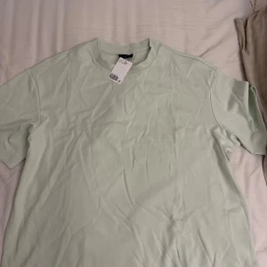 Ljusgrön basic t-shirt från H&M - Enkel och fräsch ljusgrön t-shirt från H&M. Helt oanvänd med prislapp på
