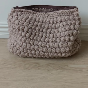 Beige virkad necessär med bubblig struktur - Superfin beige necessär med bubblig, virkad struktur och dragkedja upptill. Perfekt för smink eller hudvård. Mjuk och mysig känsla och rymlig insida. Den är hand gjord av mig💕