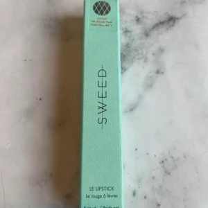 Sweed Le Lipstick Nude Pink - Sweed Le Lipstick i färgen Nude Pink kommer i en snygg mintgrön förpackning. Läppstiftet är krämigt, närande och ger en naturlig rosa nyans med nude-ton. Perfekt för dig som gillar mjuka och återfuktande läpprodukter med stilren design.