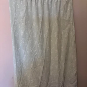 Ljusgrön blommig långkjol Vero Moda - Supersöt ljusgrön långkjol från Vero Moda med vitt blommönster. Kjolen har resår i midjan för extra komfort och är gjord i ett mjukt, lätt material som känns skönt mot huden. Perfekt för dig som gillar en romantisk och chill stil.