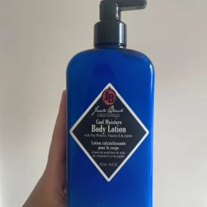 Jack Black Cool Moisture Body Lotion - Blå pumpflaska med Jack Black Cool Moisture Body Lotion, innehåller sojaprotein, vitamin E och jojoba. Ger återfuktning och fräsch känsla till huden. Flaskan rymmer 473 ml och har en stilren svart etikett med vit ram.