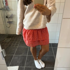 Röd blommig volangkjol - Supersöt röd kortkjol med vita små blommor och bred smock i midjan. Kjolen har volanger som ger en flowy och lekfull vibe. Perfekt för dig som gillar färg och mönster! Materialet känns lätt och luftigt, perfekt för varmare dagar.💞