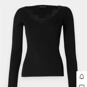 Svart ribbad topp med spets från Anna Field - Svart långärmad topp från Anna Field med ribbad struktur och v-ringning dekorerad med spetsdetaljer. Snygg och figurnära passform som passar perfekt till jeans eller kjol.