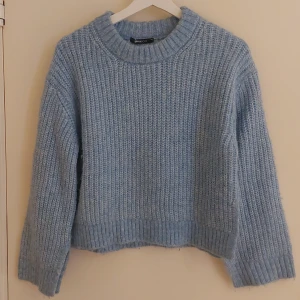 Ljusblå stickad tröja Gina Tricot XS - Supermysig ljusblå stickad tröja från Gina Tricot i storlek XS. Tröjan har grov ribbstickning, rund halsringning och långa ärmar. Den har en liten slits i nederkanten på sidorna  som ger en snygga detaljer. Perfekt för kyliga dagar!