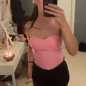 Rosa korsett med dragkedja från shein - Säljer en fin rosa korsett med hjärtformad urringning och markerade sömmar. Toppen är axelbandslös och har dragkedja bak för enkel på- och avtagning. Materialet är glansigt och perfekt att styla med jeans eller kjol 🤗💓 Har bara använt en gång innan