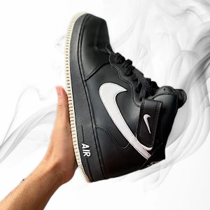 Nike Air Force 1 High svart/vit - Svarta Nike Air Force 1 High med vit swoosh och detaljer. Klassisk siluett med högt skaft, snörning och kardborreband vid ankeln. Ovandel i skinn och textilfoder för extra komfort. Perfekta för dig som gillar streetstyle och ikoniska sneakers.