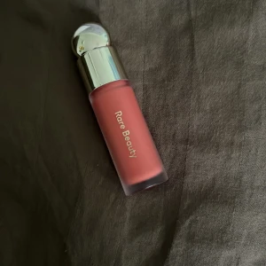 Rare Beauty Joy Liquid Blush - Använt få tal gånger. Flytande rouge från Rare Beauty i nyansen Joy, en varm persikoton. Kommer i en frostad glasflaska med silvrig rund kork. Perfekt för att ge kinderna en fräsch och naturlig glow. Innehåller 7,5 ml. 