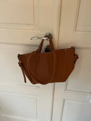 Brun handväska  - Snygg brun handväska med två handtag. Knappt använd så i bra skick! 