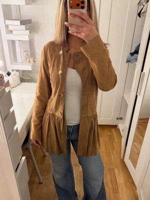 Mocka jacka  - Supersnygg jacka gjord i finaste  mockan,  med volanger i färgen ljusbrun ! storlek Xs