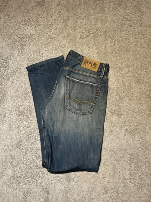 Blå Replay jeans straight fit - Säljer ett par klassiska blå jeans från Replay med raka ben och snygg slitning framtill. Perfekta för dig som vill sticka ut lite då dem är från tidigt 2000-tal. Skriv vid minsta fundering
