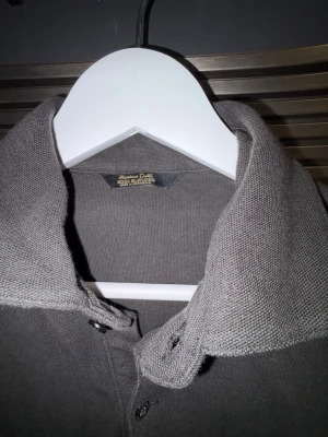 Massimo Dutti långärmad piké / tröja – wool blend (S) - Snygg långärmad tröja från Massimo Dutti i mörkgrå nyans. Klassisk krage med knäppning, funkar lika bra uppklätt som casual.  • Storlek: Small • Material: Wool blend • Skick: Bra använt skick • Passform: Normal • Inga hål eller fläckar  Perfekt till höst/vinter – passar både till jeans och kostymbyxor.
