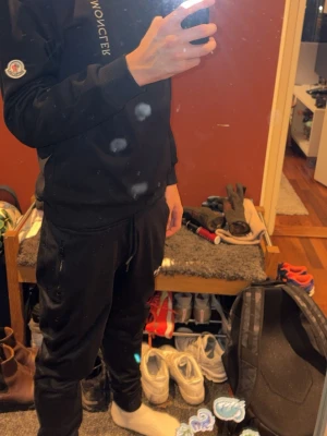 Svart Moncler hoodie med logga - Svart hoodie från Moncler med diskret logga på bröstet och klassisk Moncler-patch på ärmen. Mjuk bomullskvalitet och ribbade muddar vid ärmslut och nederkant. Perfekt för en clean och stilren look.