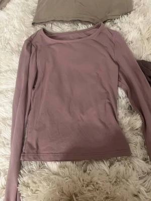 Ljuslila långärmad topp - En enkel och stilren ljuslila långärmad topp med rund halsringning. Toppen har en rak passform och är tillverkad i mjukt bomullsmaterial, perfekt för att matcha med jeans eller kjol.