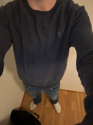 Äkta Mörkblå stickad tröja Polo Ralph Lauren - Mörkblå stickad tröja från Polo Ralph Lauren med rund halsringning och diskret broderad logga på bröstet. Tröjan har ribbade muddar vid ärmslut och nederkant. Perfekt till jeans eller chinos för en clean look.