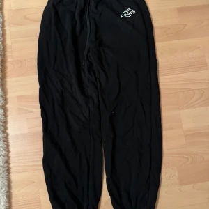 Svarta mjukisbyxor från Peach - Svarta mjukisbyxor från Peach med resår i midjan och snörning. Liten vit Peach-logga framtill. Mjukt material som känns skönt mot huden.