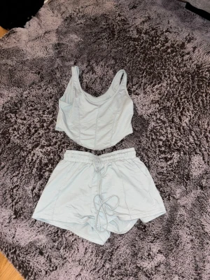 Ljusblått loungewear-set - Tvådelat loungewear-set i ljusblått med croppat linne och shorts med resår och dragsko i midjan. Perfekt för en avslappnad dag hemma. Mjukt och bekvämt material.