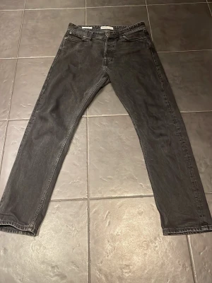 Svarta straight jeans från Jack & Jones - Säljer ett par svarta Jack & Jones jeans i klassisk straight modell. Jeansen har fem fickor, normal passform och är tillverkade i slitstarkt denimtyg av bomull. Perfekta för dig som gillar en tidlös och enkel look.