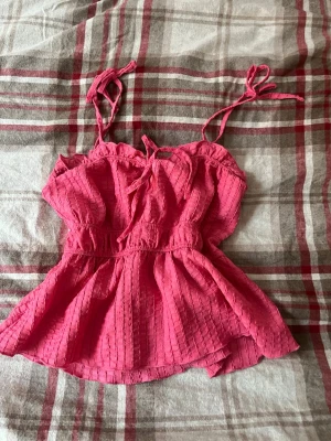 Söt rosa topp💞 - Söt rosa  topp med tunna axelband som knyts upptill. Toppen har en lätt volang nedtill och ett diskret rutigt mönster i tyget. 🩷🩷