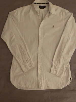 Ralph Lauren skjorta  - Klassisk vit skjorta från Polo Ralph Lauren i slim fit-modell. Skjortan har använts och testas ett fåtal gånger. Säljer nu skjortan på grund av att den är för liten för mig. Har börjat gymma nu och den är väldigt tight vid axlarna och armarna. Priset kan diskuteras vid snabba affärer, hör gärna av er vid frågor😄
