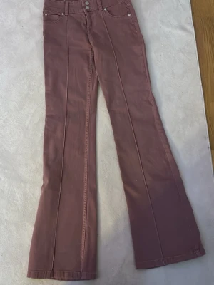 Rosa jeans - Rosa bootcut jeans från berhska. Dubbelknäppning där fram. Strl 38 men sitter som 36. Snygga och trendiga.