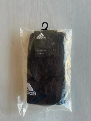 Svarta Adidas fotbollsstrumpor strl 43-45 - Säljer ett par svarta Adidas Milano 16 strumpor med vit logga och detaljer. Strumporna är tillverkade i funktionsmaterialet Climalite som transporterar bort fukt, perfekta för träning och sport. Kommer i originalförpackning med etikett.