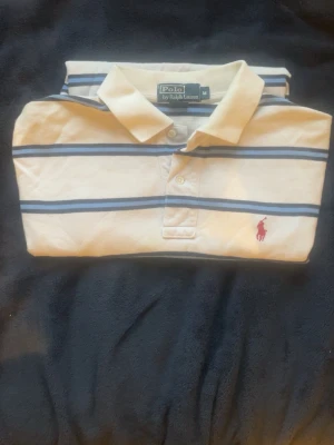 Ralph Lauren piké - Säljer nu en klassisk pikétröja från Polo Ralph Lauren i vit med marinblå och blå ränder. Storlek M, tycker den passar S också men beror på hur man vill den ska sitta. Jag kan skicka mått vid intresse. Skicket är bra, inga hål eller fläckar. Perfekt för en stilren och avslappnad look.