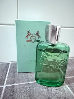 Parfums de Marly Greenley EdP 125ml - Greenley Eau de Parfum från Parfums de Marly kommer i en snygg grön glasflaska med silverfärgat lock och reliefmönster med två hästar. Förpackningen är mintgrön med silverdetaljer och logotyp. En exklusiv och modern doft för dig som gillar lyxiga parfymer. Inköpt på flygplatsen i Zürich, tyvärr så fastnade jag inte för den. Skulle uppskatta att de är ungefär ≈80% kvar i den. 125 ml. För frågor kom pm, allt gott /Neo💫