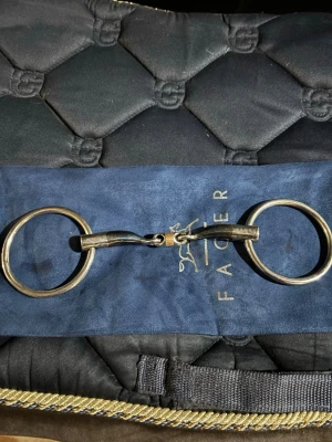 Fager Tim Sötmalm bett med lösa ringar - Säljer ett Fager Tim Sötmalm bett med lösa ringar. Bettet är i metall med blå och silverfärgade detaljer samt en mittendel som är vinklad 45 grader. Perfekt för dig som rider och vill ha ett kvalitetsbett till din häst.