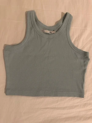 Ljusblå ribbad linnetopp från Divided - Superfräsch ljusblå croppad linnetopp från Divided. Toppen är ribbad och ärmlös med rund halsringning, perfekt till jeans eller kjol. Enkel och stilren design som passar till många olika looks.