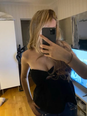 Svart axelbandslös tubtopp - Snygg svart axelbandslös tubtopp med bandeau-modell. Toppen har en enkel och stilren design som passar perfekt till jeans eller kjol. Materialet känns mjukt och följsamt mot huden och toppen sitter uppe utan axelband⭐️