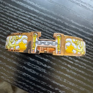 Äkta Clic H armband rosé, gul och vit, med kvitto - Snyggt äkta Clic H armband i rosémetall med vit och gul emalj. Armbandet har ett klassiskt H-spänne och detaljerat mönster med kedjor och figurer i gult och vitt. Perfekt statement piece för dig som gillar lyxiga accessoarer. Storlek GM, originalkvitto från NK medföljer. För skick se bilder. Fler bilder finns  😊