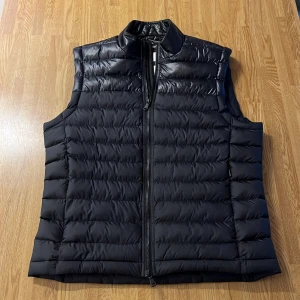 Svart dunväst från J.Lindeberg - Snygg svart väst från J.Lindeberg. Västen är i nyskick och använd 1 gång bara! Säljer för att jag ej har användning för den. Nypris ca 1800kr. Skriv vid frågor om mått osv! Pris kan diskuteras vid snabb affär!