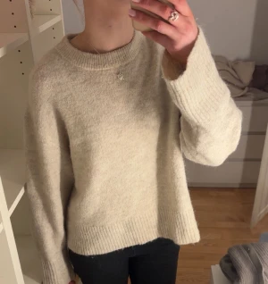 Beige stickad tröja - Mysig beige stickad tröja med rundad hals och breda ribbade muddar vid ärmslut och nederkant. Tröjan har en loose passform och långa ärmar, perfekt för att hålla sig varm under kyliga dagar. Enkel och stilren design som är lätt att matcha. Passar som stl S!💕