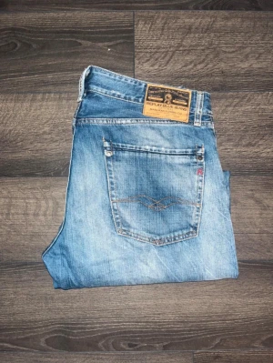 Replay Rogob jeans blå straight fit - Snygga Replay Rogob jeans W33 L32 i klassisk blå tvätt med slitningar och raka ben. Perfekt passform för dig som gillar en avslappnad stil.