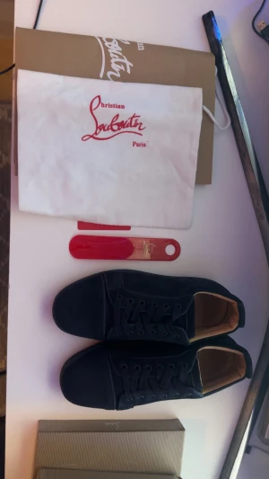 Mörk blå  sneakers från Christian Louboutin - Säljer ett par mörk blå  sneakers från Christian Louboutin i mocka med klassisk röd sula och rund tå. Skorna har snörning och diskret broderad logga på hälen. Insidan är beige och de kommer med originalpåse och skohorn.