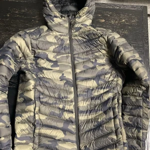 pufferjacka Peak Performance - Säljer en fet pufferjacka från Peak Performance i storlek M. Jackan har camouflage-mönster i grått och beige, Perfekt för dig som vill sticka ut med en cool look och hålla dig varm under kalla dagar.  Den finns inte inte längre så passa på . Den är ganska lite använt nästan som ny . 