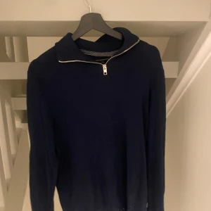 Marinblå stickad tröja med half zip - Snygg marinblå stickad tröja med half zip i halsen. Tröjan har långärmade ärmar och en klassisk krage som ger en chill och stilren vibe. Perfekt för dig som gillar enkel men ändå trendig stil. Passar till jeans eller chinos.