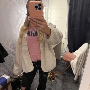 Beige teddyjacka från H&M - Supermjuk och oversized teddyjacka från H&M i beige färg. Jackan har rund hals, tryckknappar framtill och två fickor. Perfekt för lager-på-lager och chill vibes. Materialet är fluffigt fleece som håller dig varm under kyliga dagar.