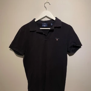 Svart pikétröja från GANT - Klassisk svart pikétröja från GANT i bomull med liten broderad logga på bröstet. 