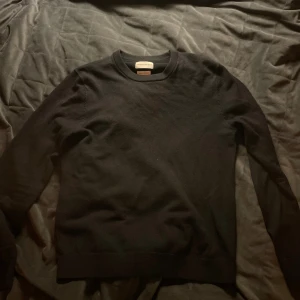 Mörkblå merinotröja - Svart, stilren tröja från These Glory Days i mjuk superior merinoull. Klassisk rund hals och långärmad modell med ribbade muddar. Perfekt för dig som gillar minimalistisk look och vill ha något som är både bekvämt och snyggt.