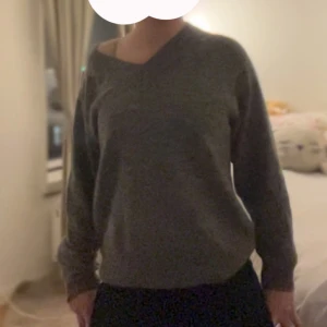 Grå stickad v-ringad tröja - Mysig grå stickad tröja med v-ringad hals och långärmade ärmar. Tröjan har en loose passform och är perfekt för kyliga dagar. Materialet är mjukt och ger en chill vibe, enkel att matcha med jeans eller kjol.