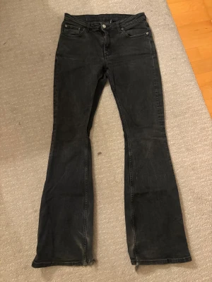 Svarta bootcut jeans från Flame - Svarta jeans från Flame med bootcut passform och klassisk femficksdesign. Jeansen har låg midja. Slitna där nere 