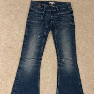 Blå bootcut jeans från Gina Tricot XS - Snygga blå bootcut jeans från Gina Tricot i storlek XS. Jeansen har slitna detaljer framtill, klassiska fickor och låg midja. Materialet är jeans med en tvättad look och lätt utsvängda ben för en trendig siluett. Är helt oanvända och bara legat i min låda. Därför priset!