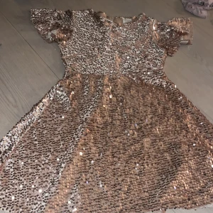 Klänning,  Glittrig champagneklänning , Zara Kids - Superfin glittrig klänning från Zara Kids i champagnefärg med paljetter över hela plagget. Klänningen har korta ärmar, rund halsringning och dragkedja i ryggen. Perfekt för dig som vill glänsa! Storlek 140(10)